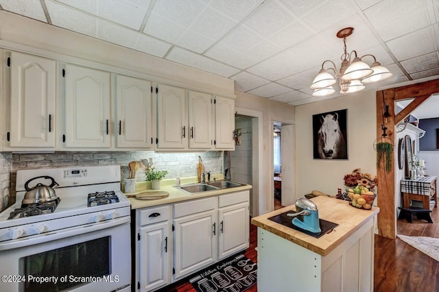 kitchen featuring white cabinetry, sink, a drop ceiling, hanging light fixtures, and white range with gas cooktop