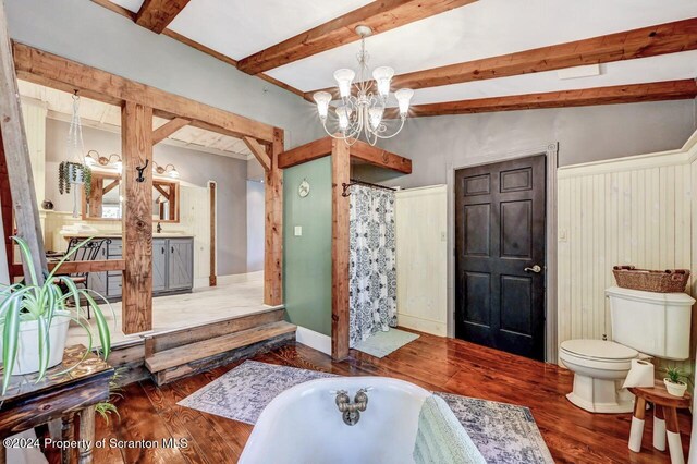 interior space with wood-type flooring, lofted ceiling with beams, a bath, an inviting chandelier, and toilet