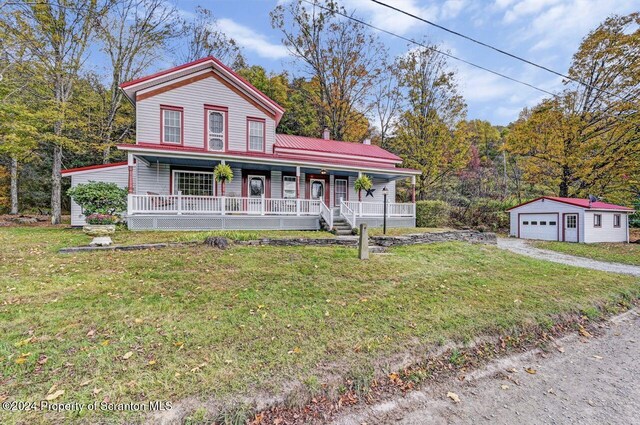 view of front of home with an outbuilding, a garage, a front lawn, and covered porch