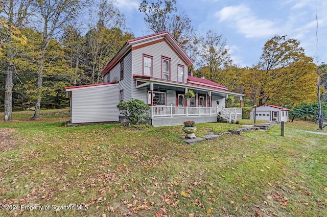 view of front facade featuring a front yard, a porch, a garage, and an outdoor structure