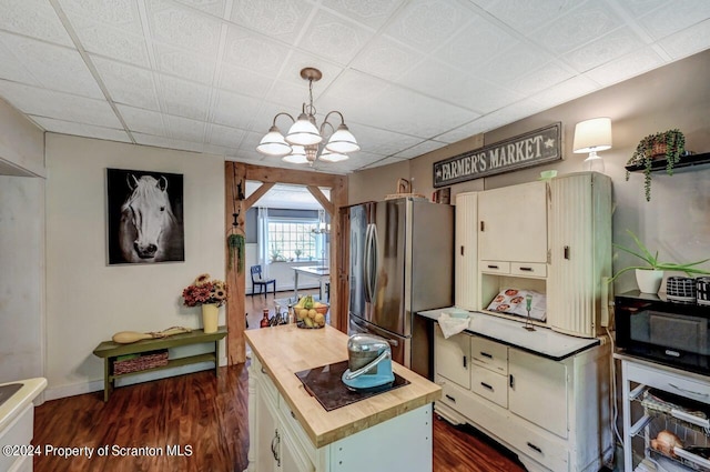 kitchen with stainless steel fridge, decorative light fixtures, a kitchen island, butcher block counters, and a chandelier