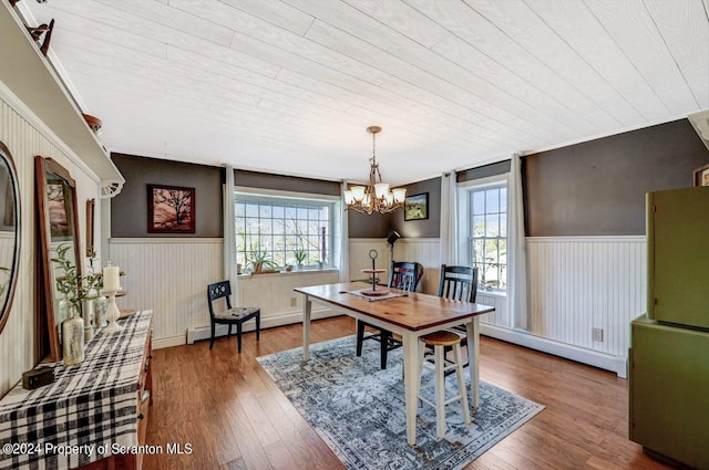 dining area featuring wood-type flooring, baseboard heating, a notable chandelier, and wood ceiling