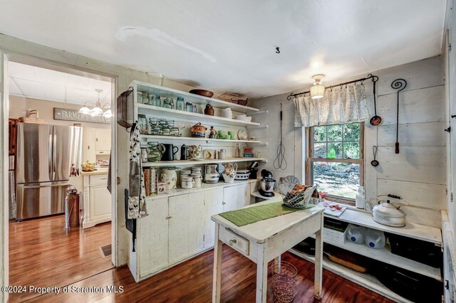 kitchen featuring hardwood / wood-style flooring, white cabinets, stainless steel refrigerator, and a chandelier