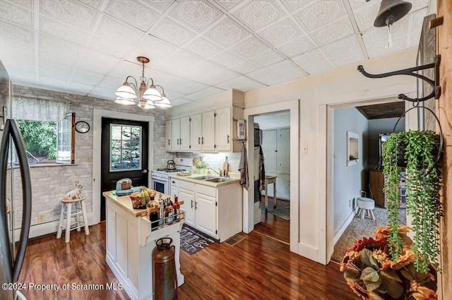 kitchen featuring dark wood-type flooring, an inviting chandelier, white cabinets, refrigerator, and white range with gas cooktop