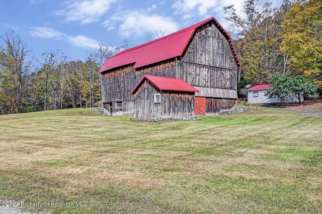 view of property exterior with a lawn and an outdoor structure