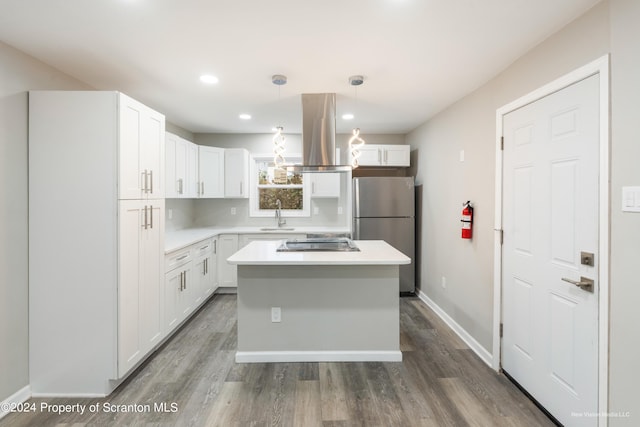 kitchen featuring island exhaust hood, white cabinetry, decorative light fixtures, and appliances with stainless steel finishes