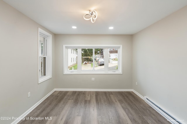 spare room with baseboard heating and wood-type flooring