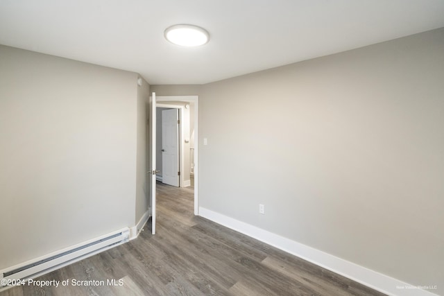 spare room with hardwood / wood-style flooring and a baseboard heating unit