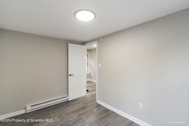 spare room featuring baseboard heating and dark wood-type flooring