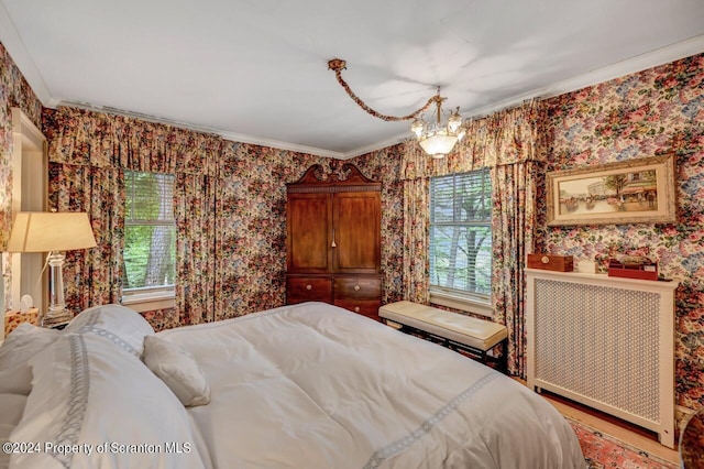 bedroom with hardwood / wood-style floors, a notable chandelier, ornamental molding, and radiator