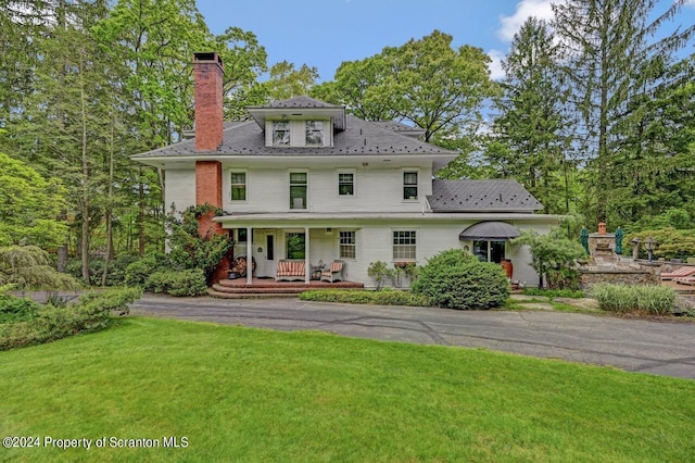 back of house with covered porch and a yard