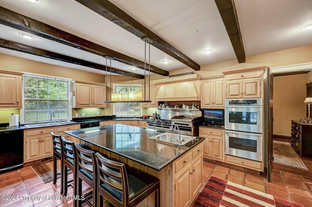 kitchen with beam ceiling, light brown cabinets, dishwasher, stainless steel double oven, and a kitchen island with sink