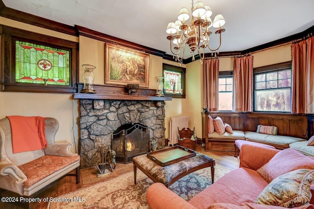 living room featuring radiator, an inviting chandelier, light wood-type flooring, ornamental molding, and a fireplace