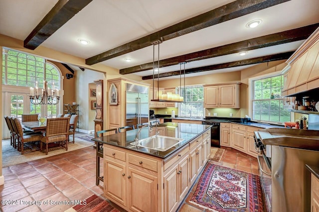 kitchen featuring sink, dishwasher, built in refrigerator, decorative light fixtures, and a kitchen island with sink