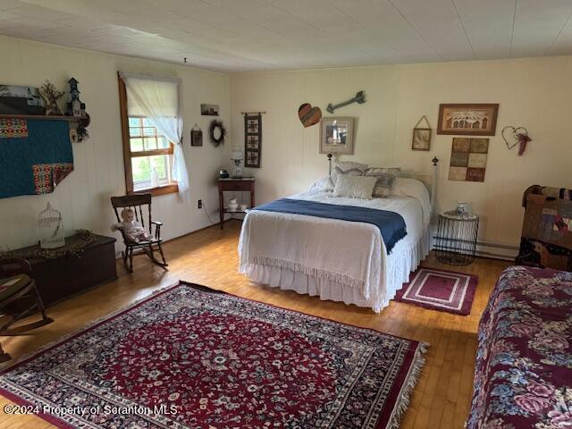 bedroom featuring hardwood / wood-style floors and a baseboard radiator