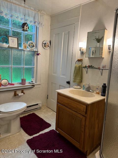 bathroom with tile patterned floors, vanity, a wealth of natural light, and a baseboard radiator