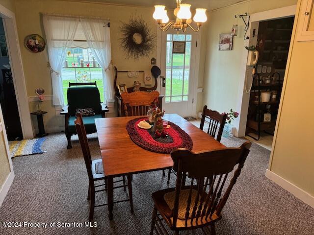 dining area with dark colored carpet and a notable chandelier