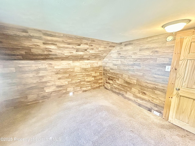 spare room with lofted ceiling and wooden walls