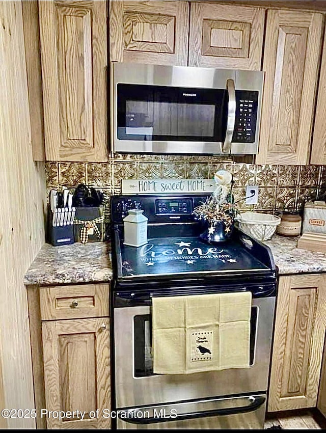 kitchen featuring light stone counters, stainless steel appliances, and decorative backsplash