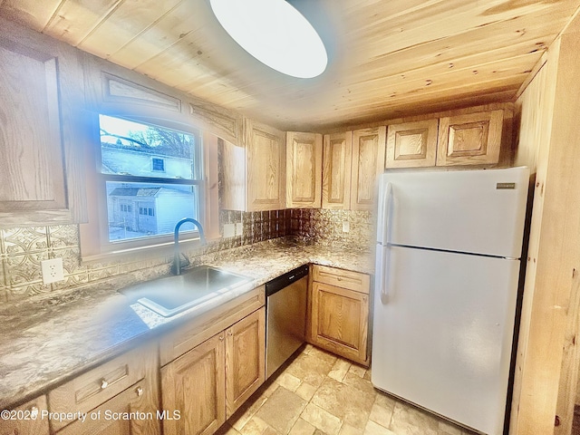 kitchen featuring a sink, light countertops, stainless steel dishwasher, freestanding refrigerator, and tasteful backsplash