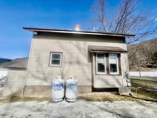 view of side of property featuring a chimney and metal roof