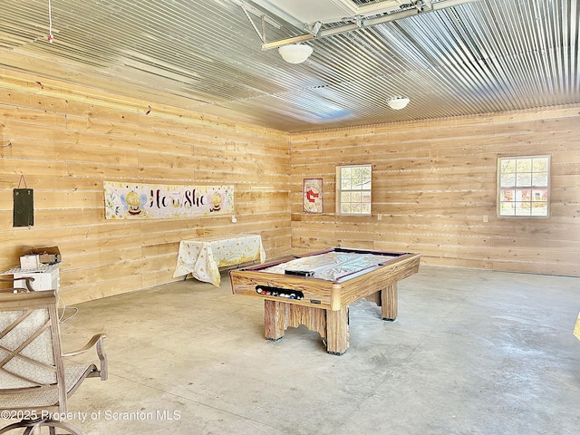 recreation room with concrete floors and wooden walls