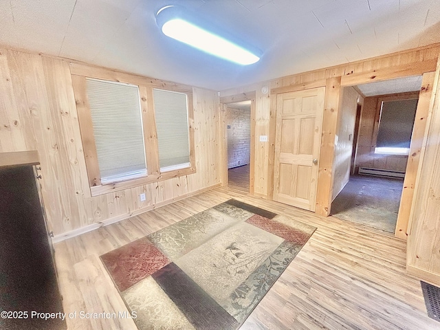 spare room featuring wood walls, a baseboard radiator, and wood finished floors