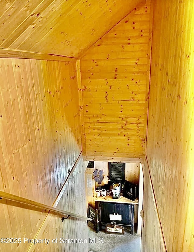 staircase with vaulted ceiling, wooden ceiling, and wooden walls