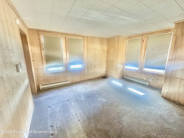 unfurnished room featuring a baseboard heating unit, wood walls, baseboard heating, and visible vents