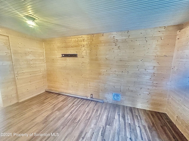 unfurnished room with wood finished floors and wooden walls