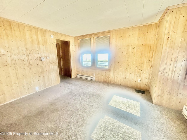 empty room featuring carpet floors, wood walls, a baseboard radiator, and visible vents