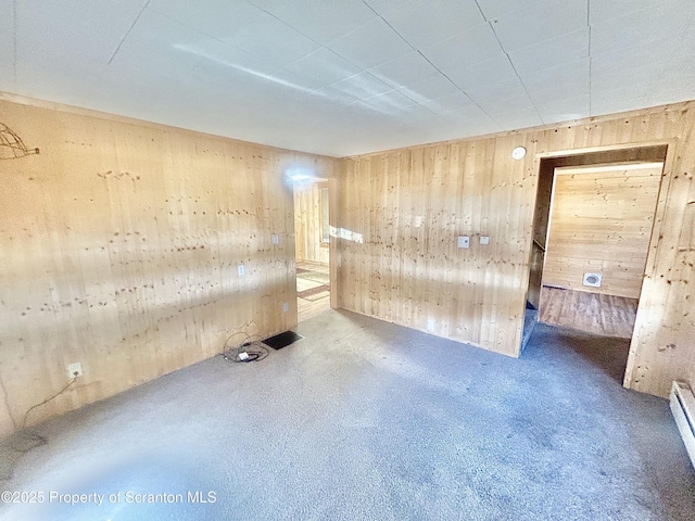 spare room with concrete floors, wooden walls, and baseboard heating