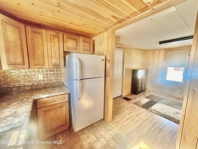 kitchen featuring tasteful backsplash, brown cabinetry, freestanding refrigerator, wood walls, and wooden ceiling