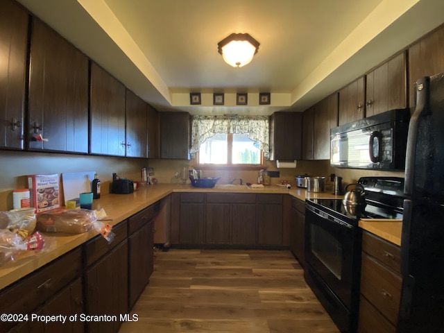 kitchen featuring black appliances, dark brown cabinets, sink, and hardwood / wood-style floors