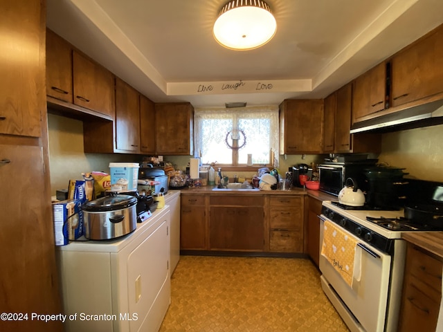 kitchen featuring a raised ceiling, washer / clothes dryer, sink, and white range with gas stovetop