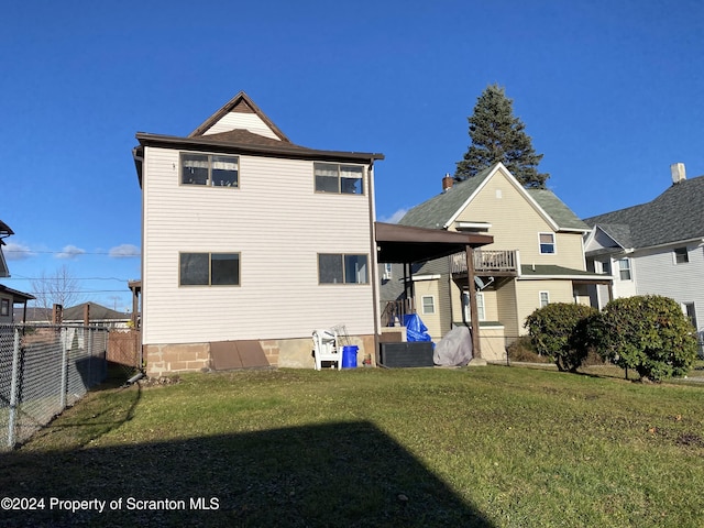 rear view of property with a yard and a balcony