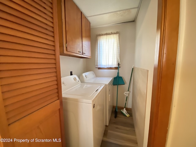 clothes washing area with cabinets, independent washer and dryer, and light hardwood / wood-style flooring