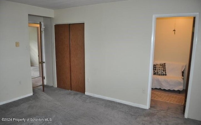 unfurnished bedroom with dark colored carpet and a closet