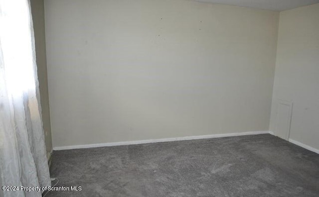 unfurnished room with dark carpet