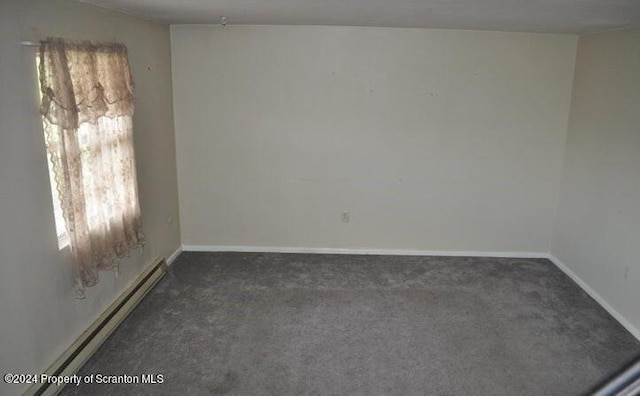 spare room featuring dark colored carpet and a baseboard radiator