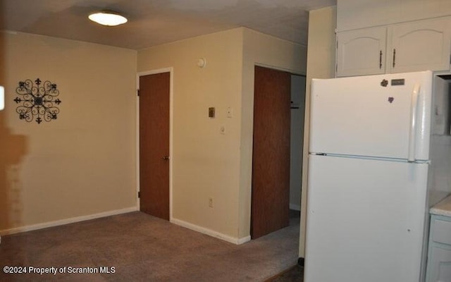 kitchen featuring white cabinets, white fridge, and dark carpet