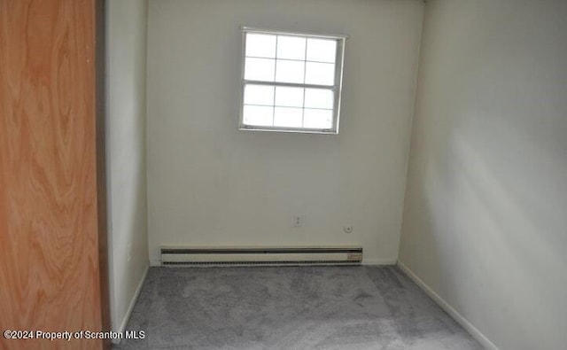 carpeted spare room with a baseboard heating unit