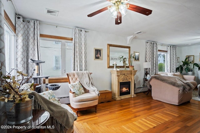 living area featuring a baseboard radiator, parquet floors, and ceiling fan