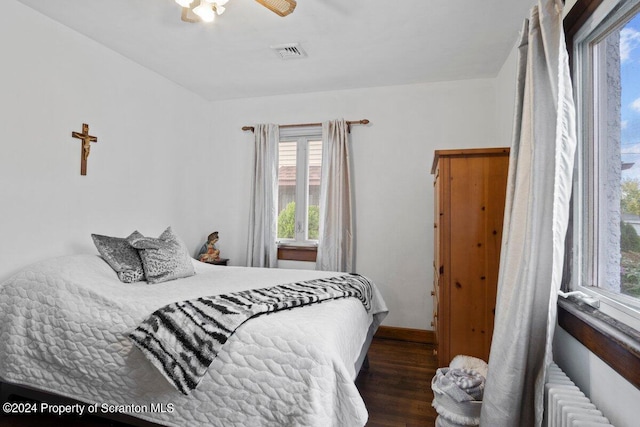 bedroom with radiator heating unit, dark hardwood / wood-style floors, and ceiling fan