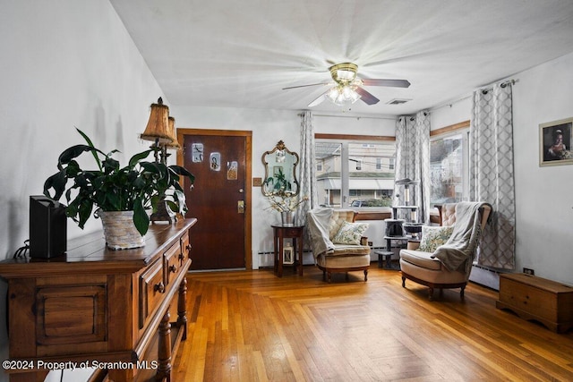 sitting room with ceiling fan, wood-type flooring, and baseboard heating