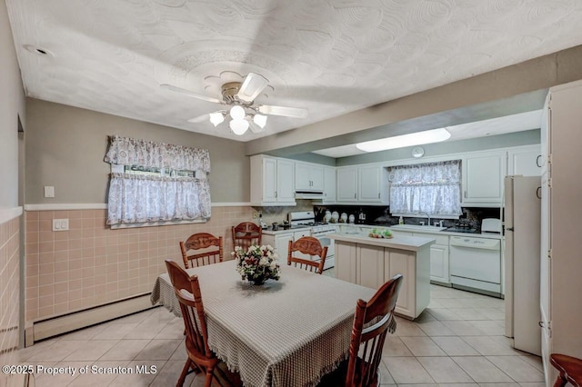 1130 Stafford Ave, Scranton, PA 18504 - dining room featuring a baseboard heating unit, light tile patterned floors, wainscoting, ceiling fan, and tile walls
