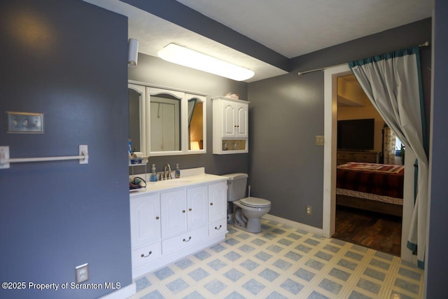 bathroom with connected bathroom, baseboards, toilet, and vanity