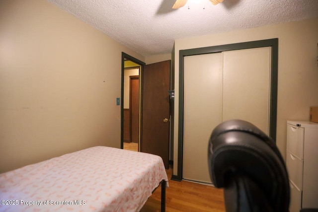 bedroom with light wood-style flooring, a ceiling fan, a closet, and a textured ceiling