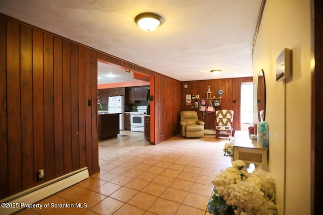 unfurnished living room with light tile patterned floors, baseboard heating, and wooden walls