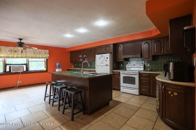 kitchen with backsplash, white appliances, a kitchen bar, and a sink